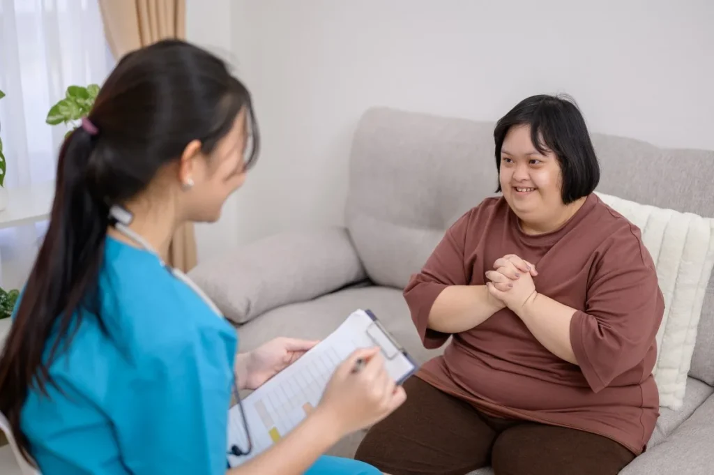 Nurse at home talking with happy disabled woman