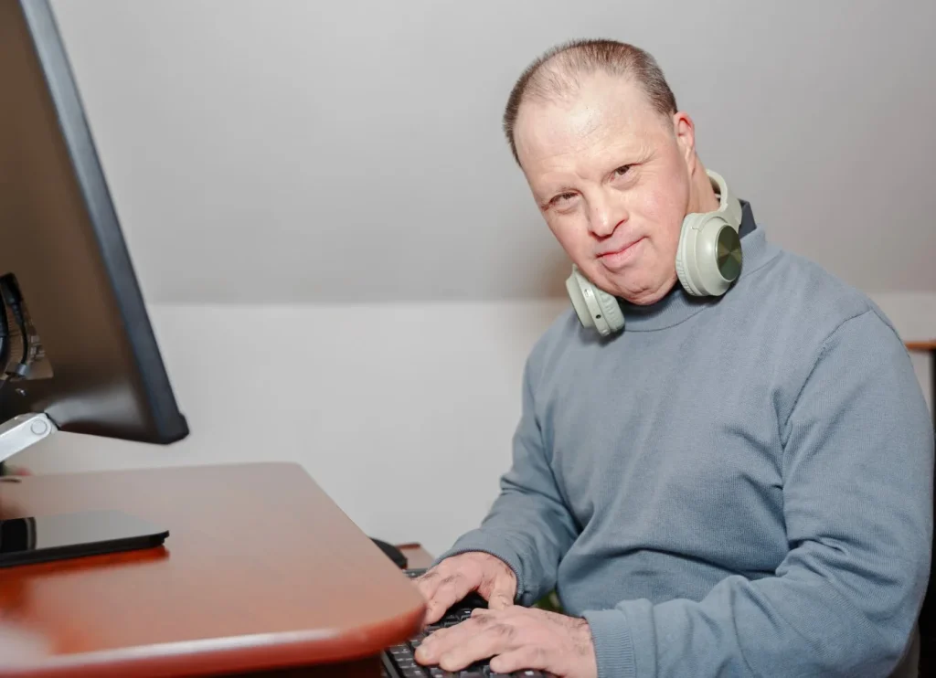 Smiling disabled man using computer and looking at camera