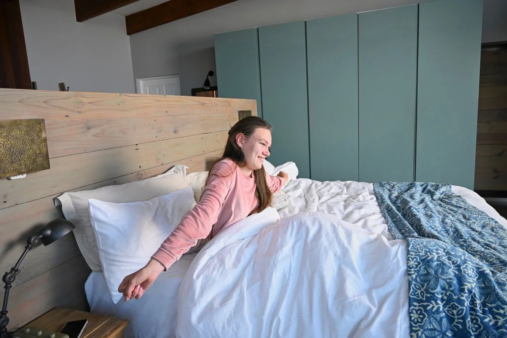 Happy disabled girl in bed stretching and smiling