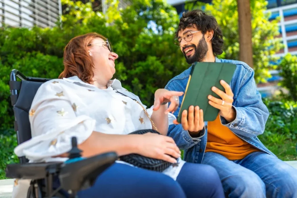 Support Coordinator looking at iPad with disabled woman in wheelchair, both smiling