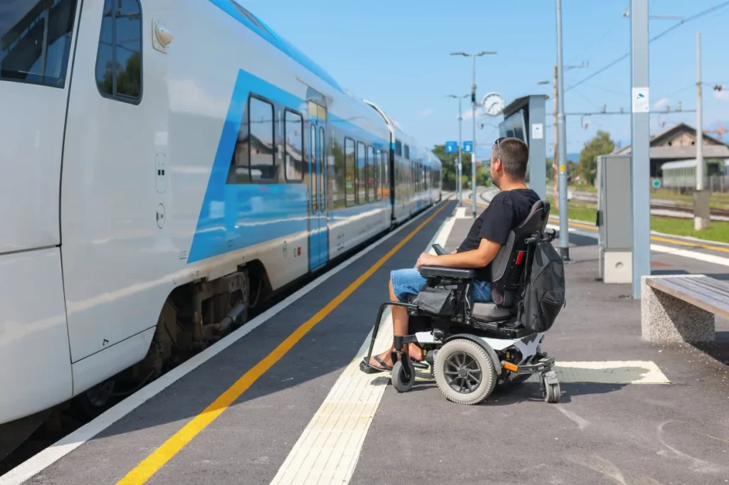 Disabled man in wheelchair waiting on train platform to board train