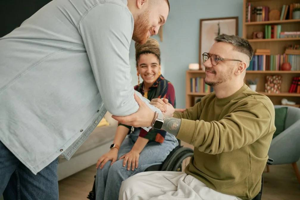 Two friends smiling at each other, one disabled in wheelchair